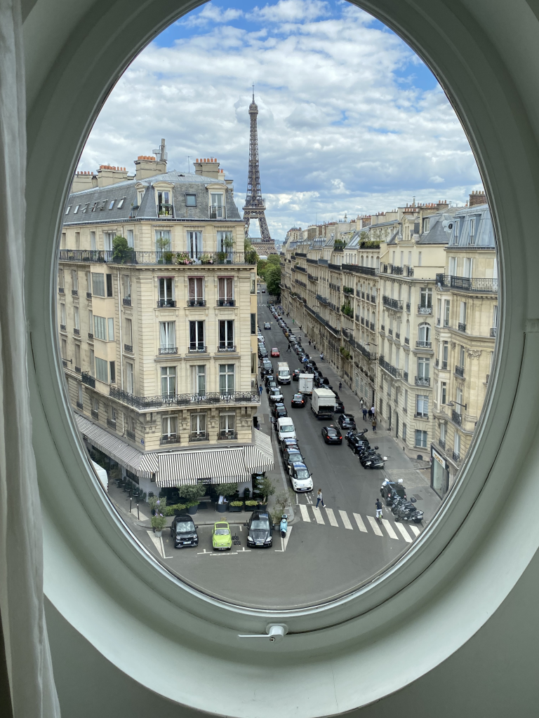 Paris, France; picture of the Eiffel tower through the view of a circular hotel room window 
