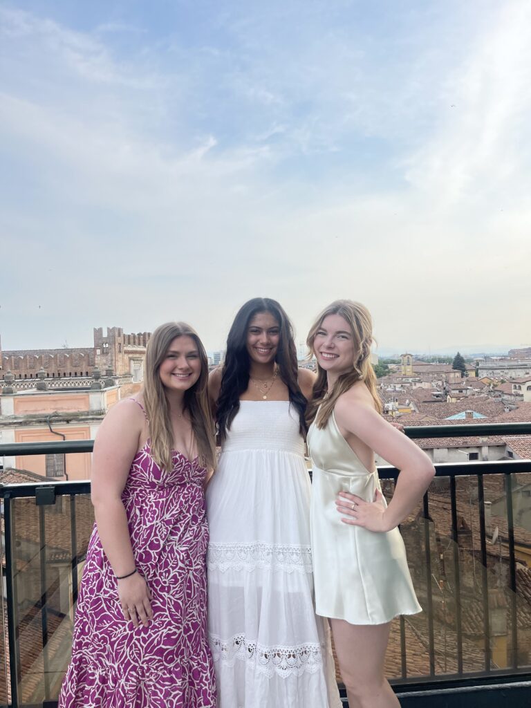 Emma on the right posing with two friends on a balcony in Italy.