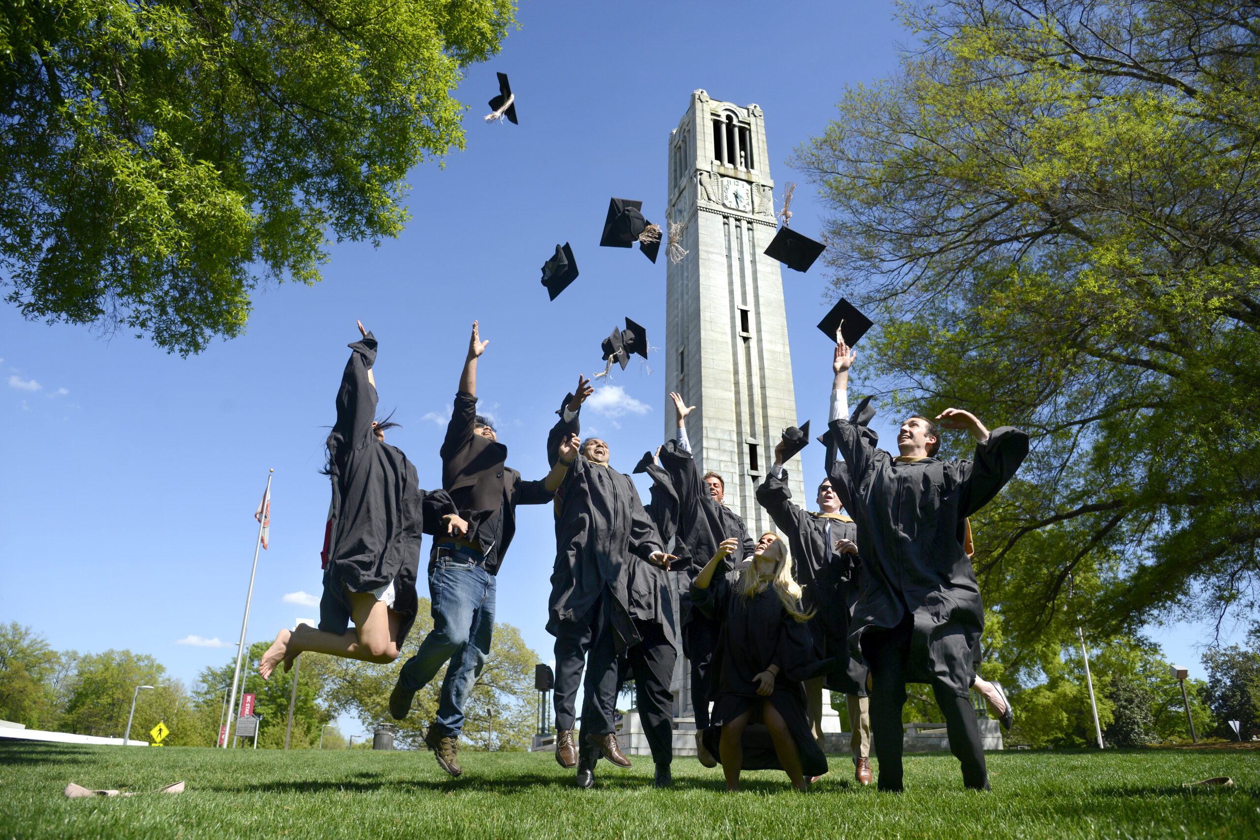 Graduates tossing hats with tower in the background