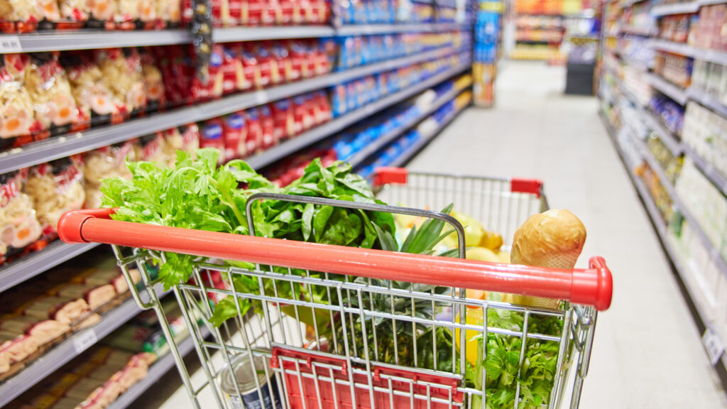 Shopping cart with many foods in a corridor in the supermarket