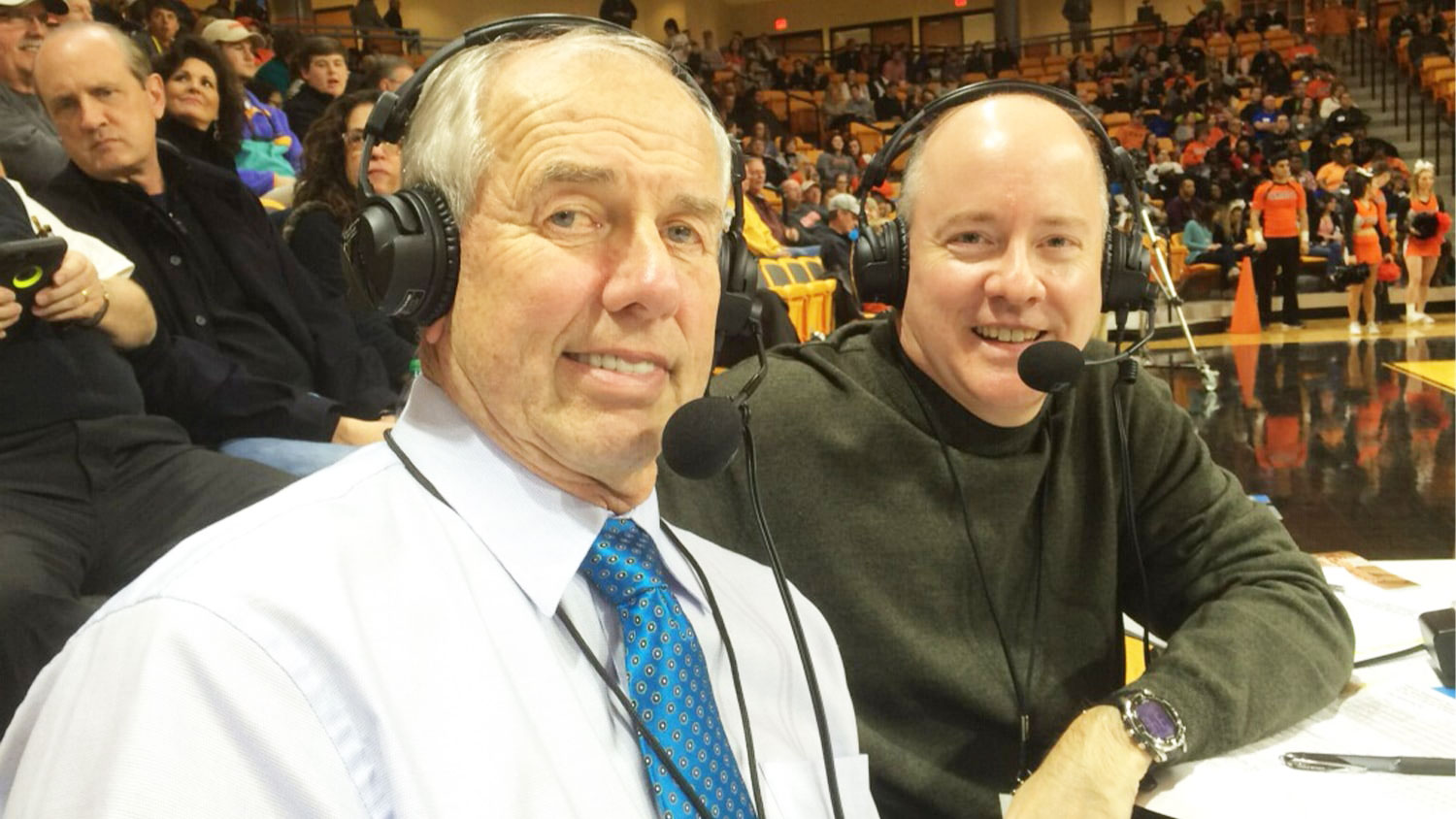 two men wearing radio headsets at a basketball game
