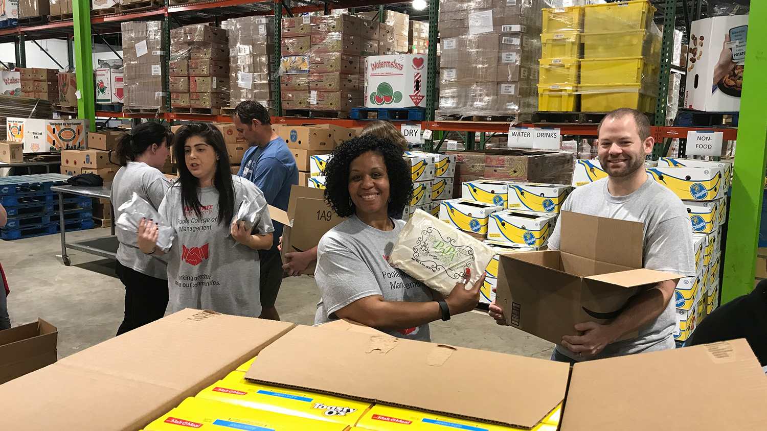 Stefani Ashkinazy, Deborah Wilkins and Brian Peters in the midst of taking food from shipping containers and packing into smaller boxes for delivery to Food Bank of Eastern and Central North Carolina clients.