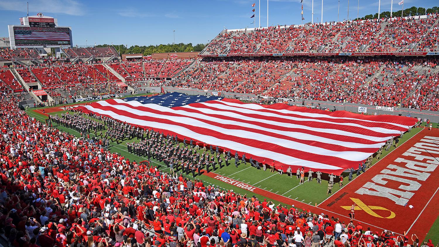 The American flag covers the field during a presentation at half time during the 2017 Military Appreciation Day at Carter-Finley Stadium.