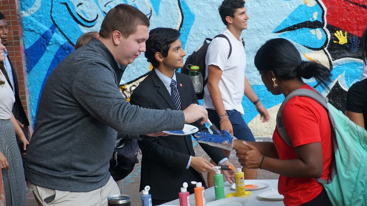 Student Body Vice President Isaac Carreno and other Student Government representatives help students paint their hands to leave their handprints on the mural at Respect the Pack.