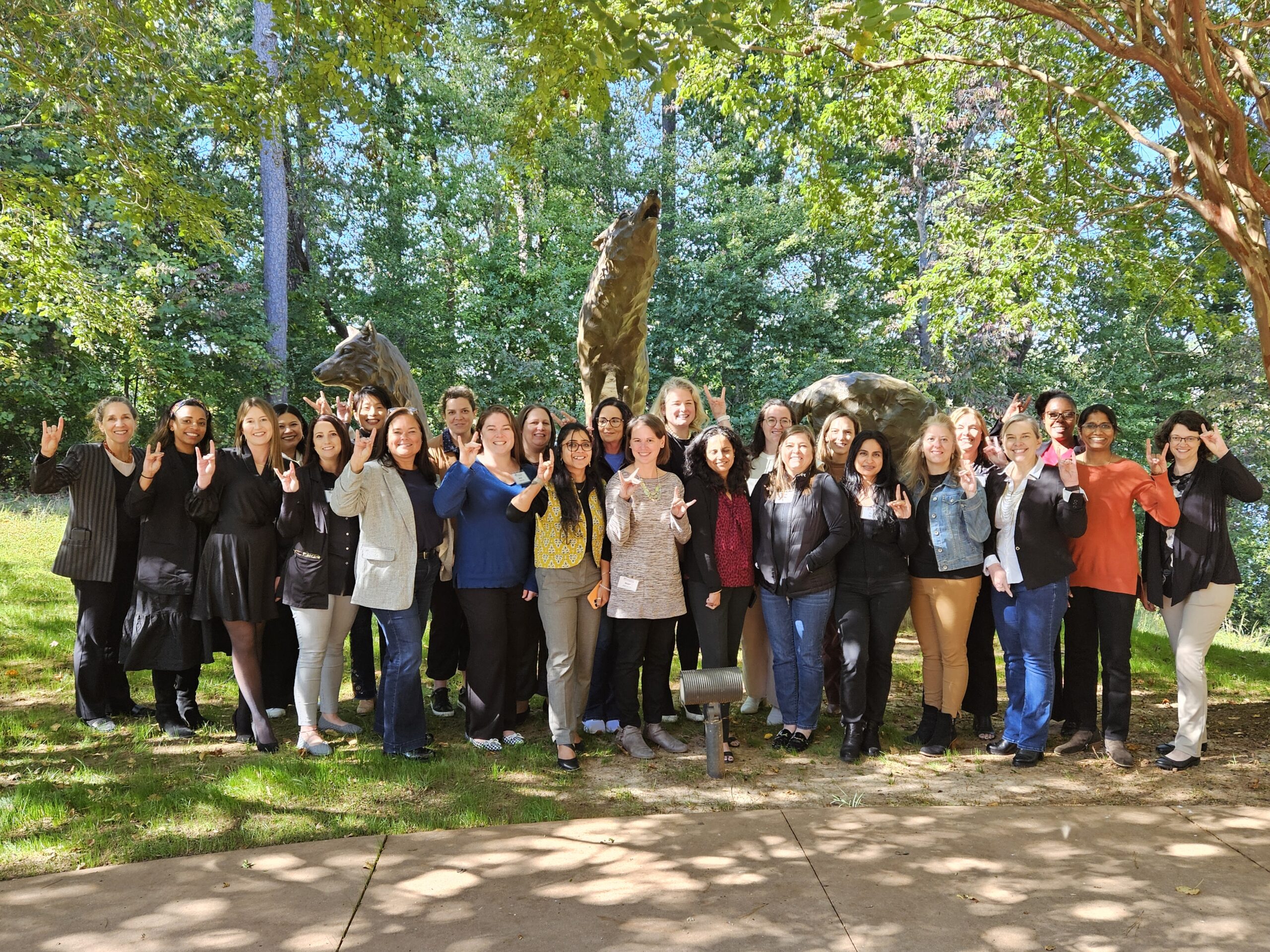 Women in Technical Leadership program participants make wolfpack sign