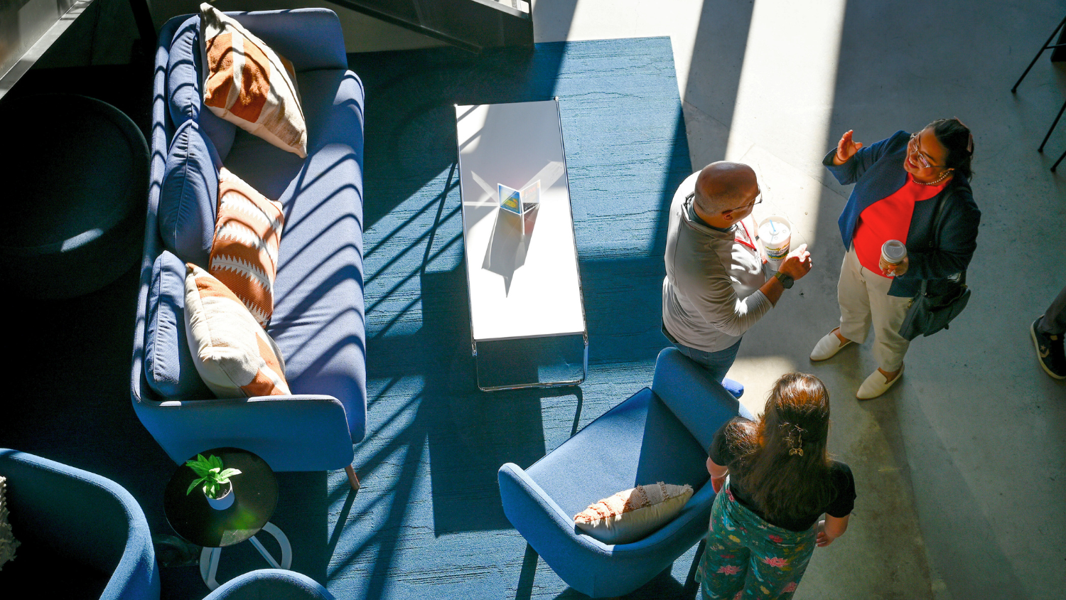 people mingling in a room with blue furniture