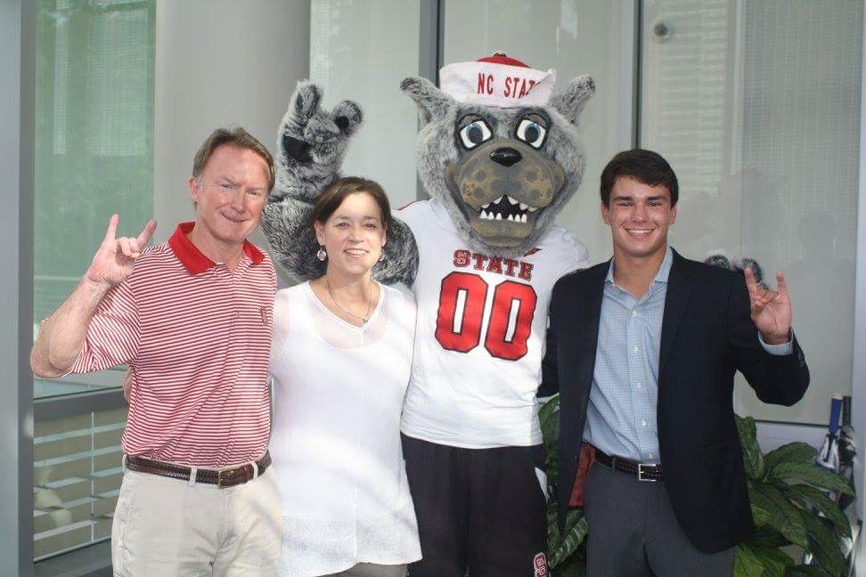 Jack Tucker, his parents, and Mr Wuf making the wolfpack sign