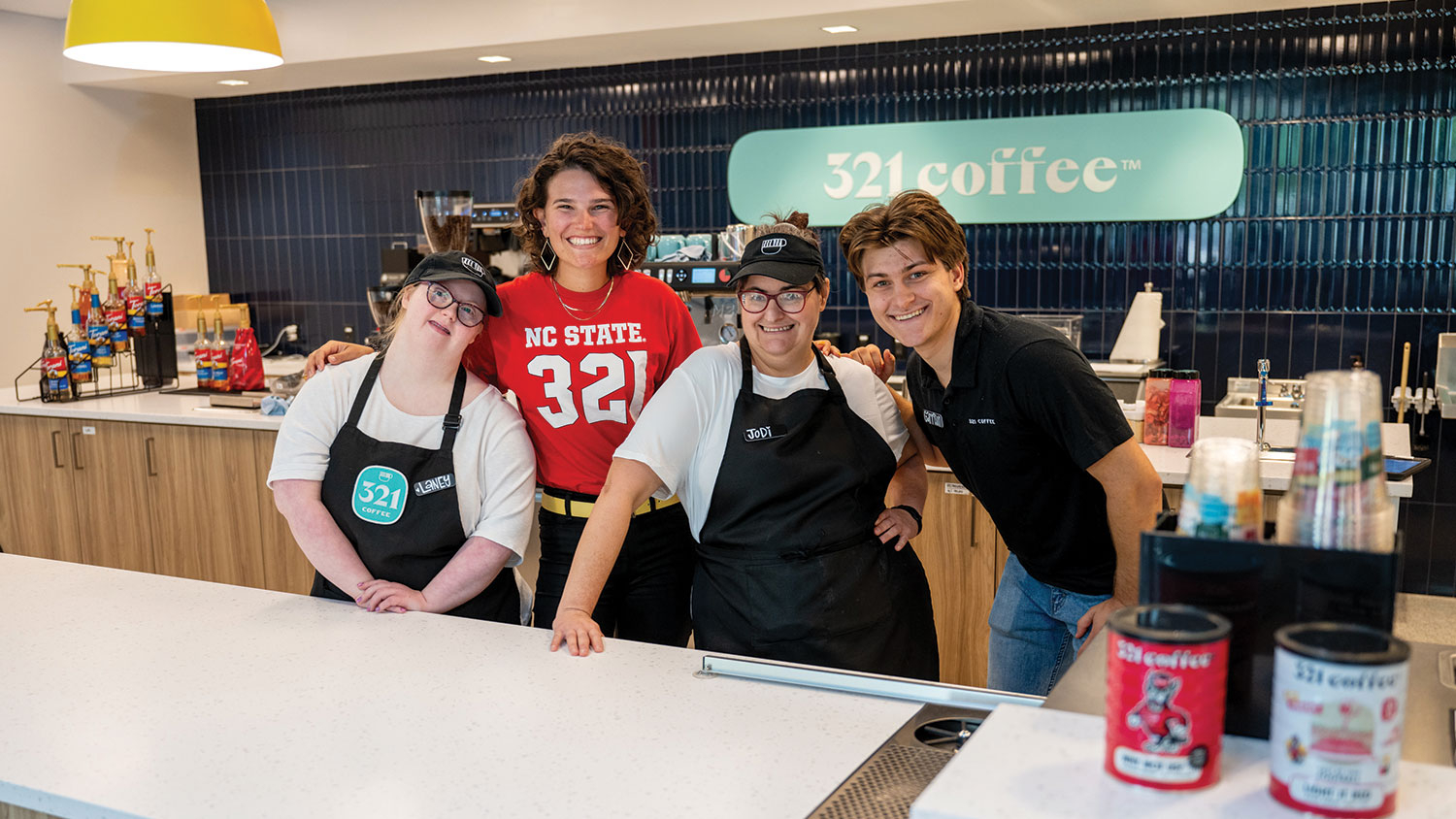 Owner of and workers at 321 Coffee on Centennial Campus stand behind their counter.