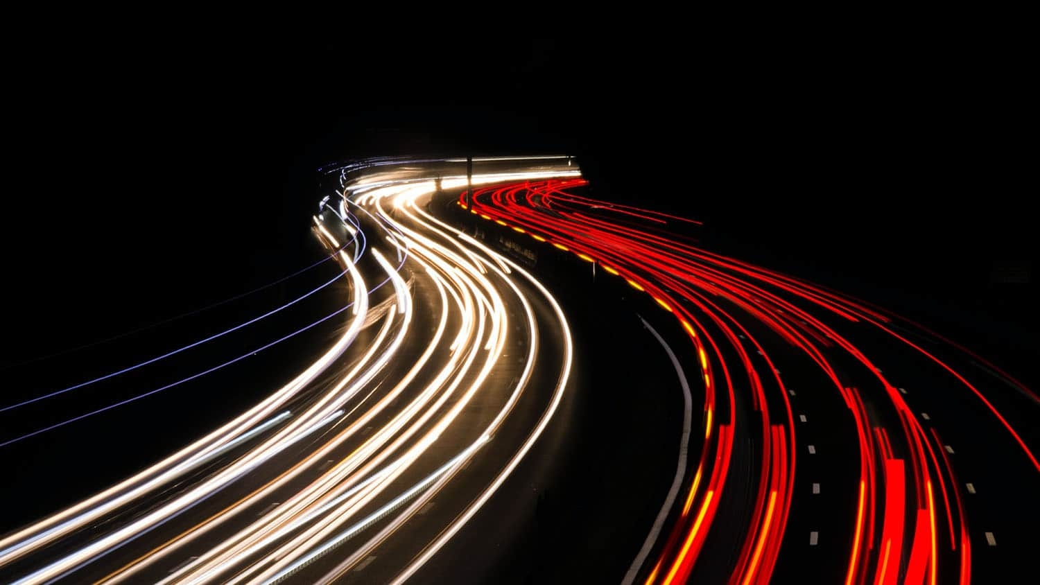 night-time photo shows two lines of traffic, one moving toward the camera, and one moving away from the camera
