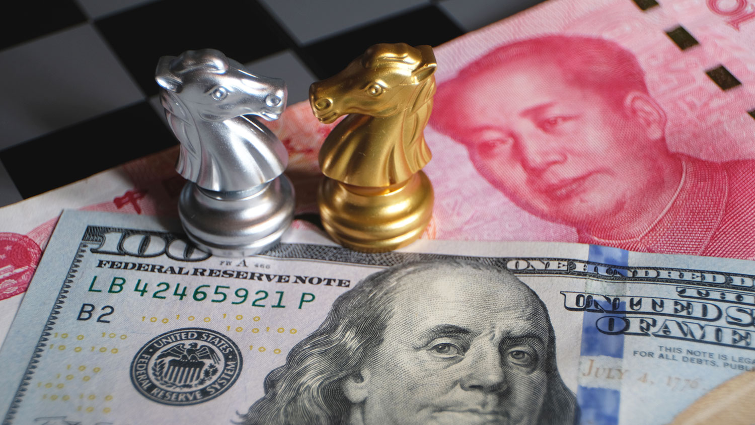 chess game, two knights face to face on Chinese yuan and U.S. dollar background