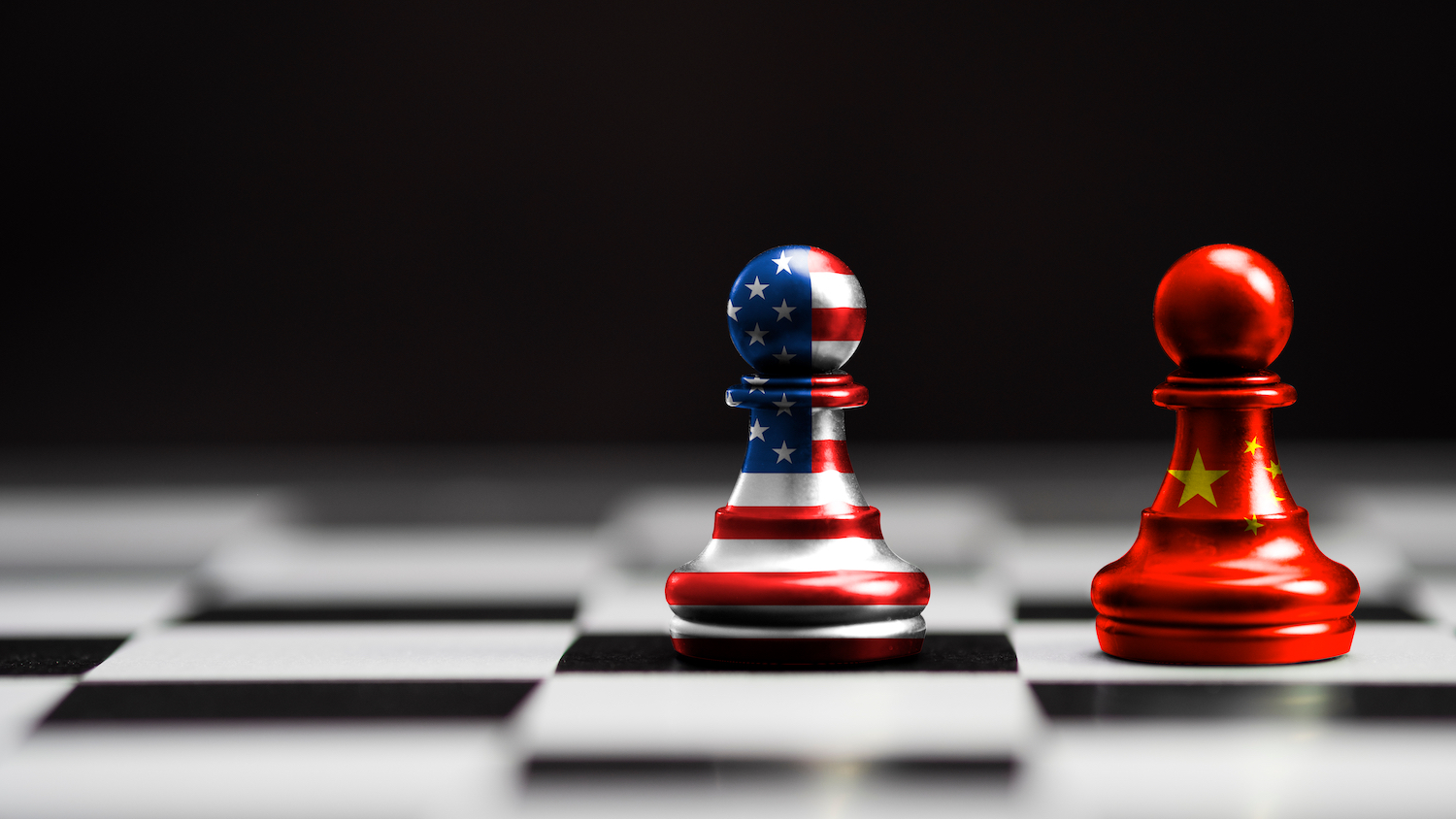 Two pawns sit side-by-side on a chess board. One is colored like the America flag, one like the Chinese flag.