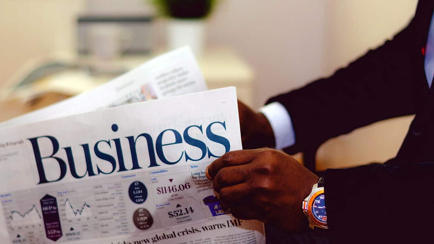 a man in a suit is holding the business section of a newspaper