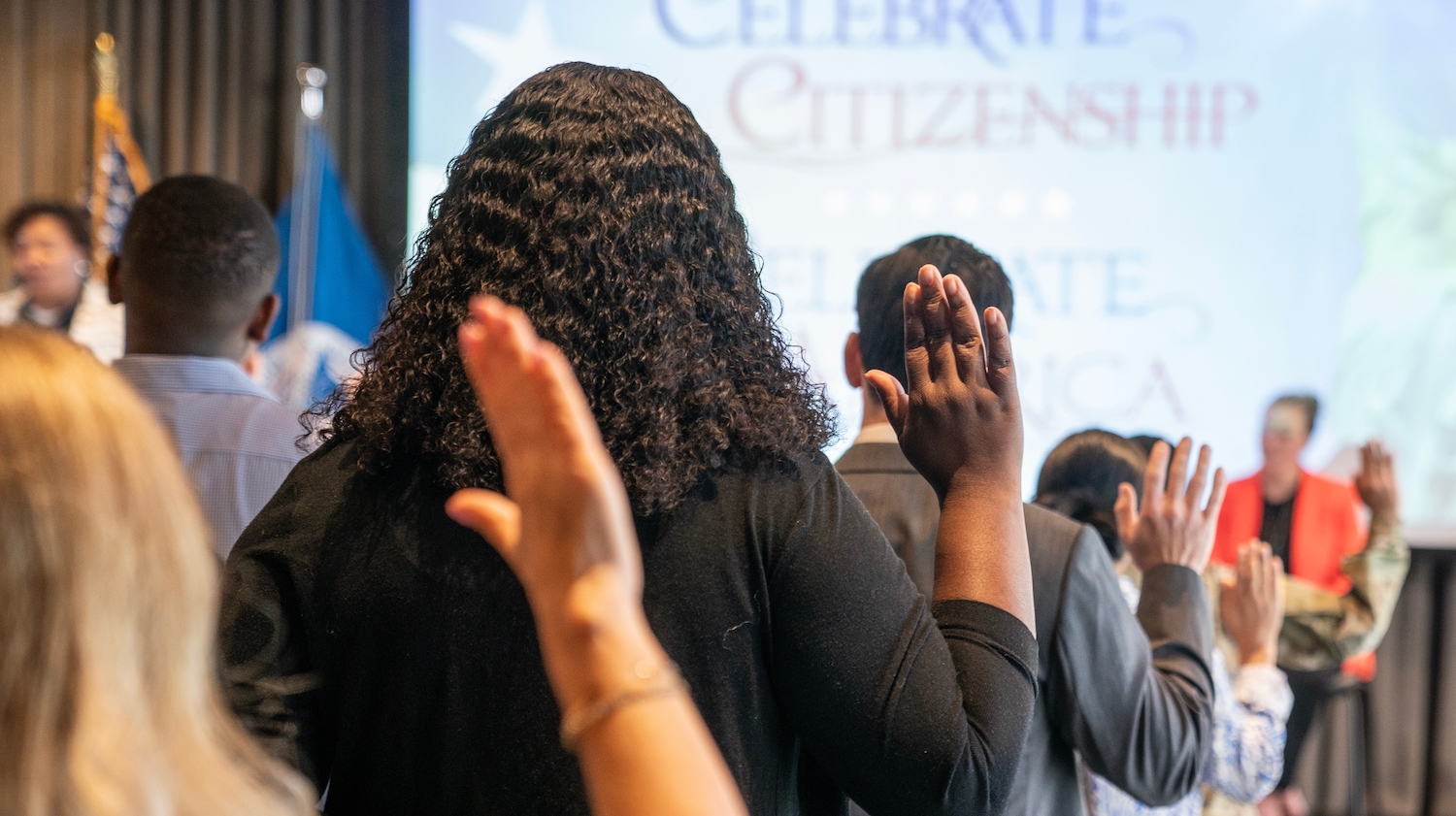 People facing away from the camera raise their right hands and swear an oath.