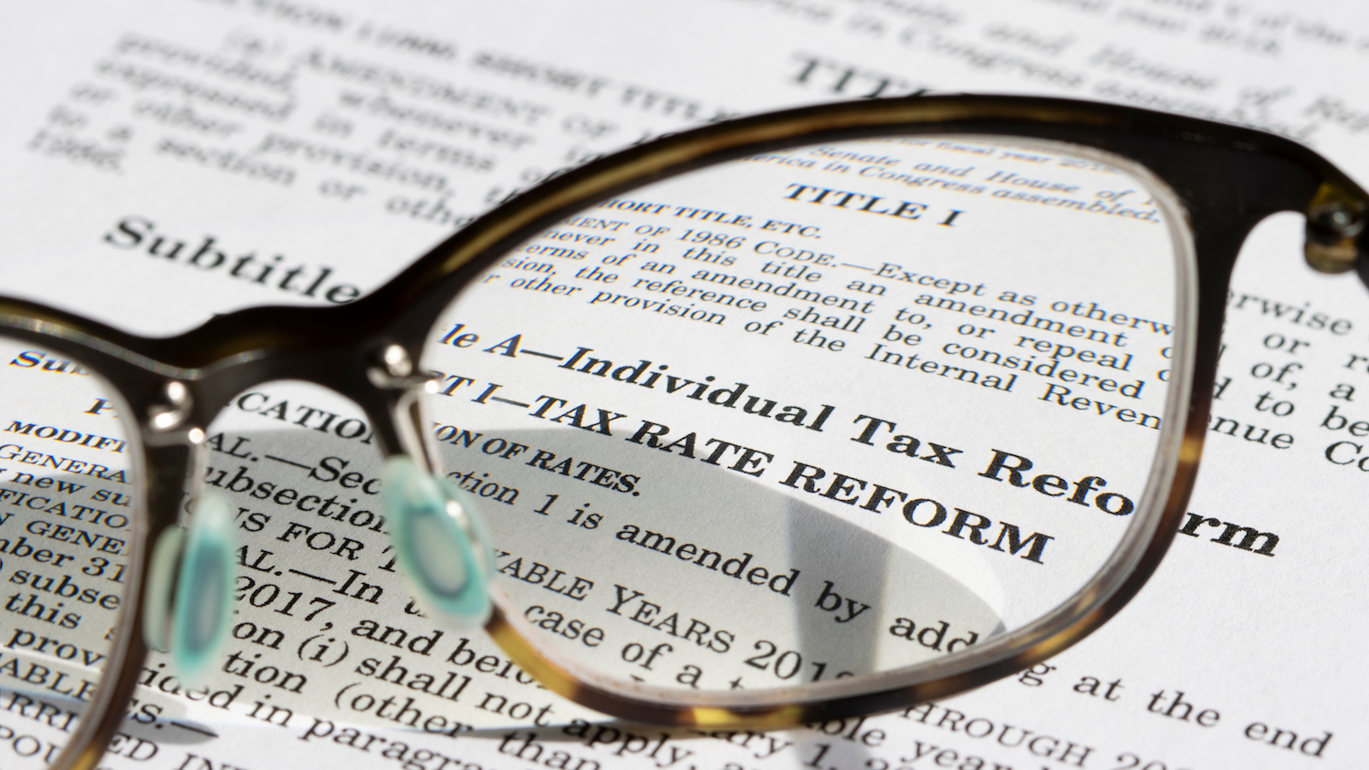 A pair of eyeglasses sits on a printout of federal tax legislation.