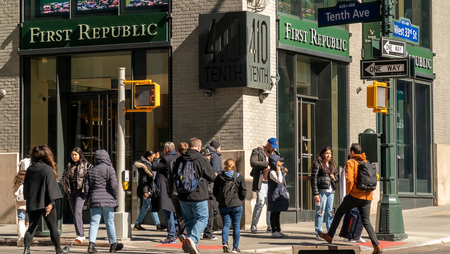 People stand on a busy street corner in front of a First Republic Bank branch in New York City.