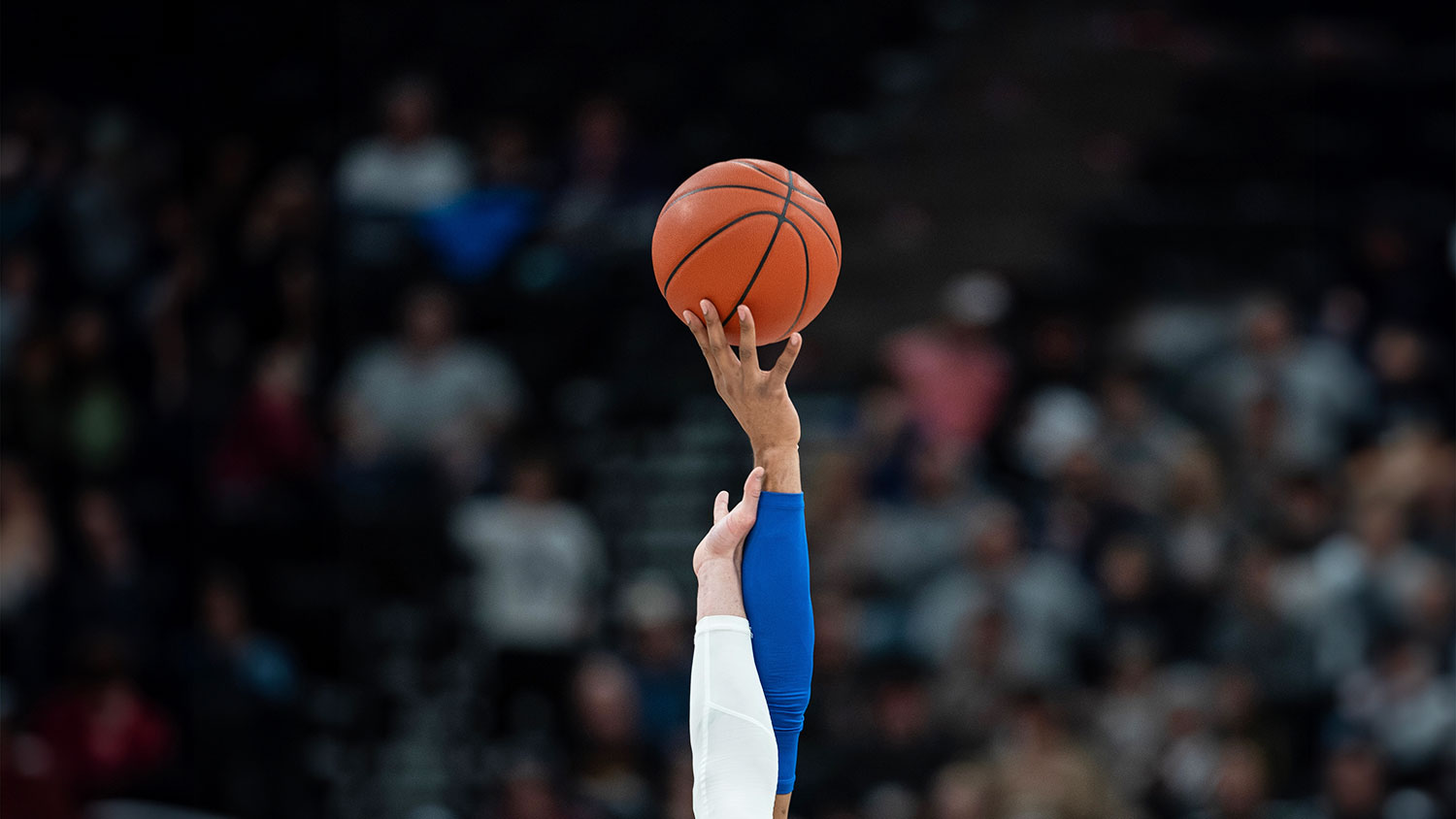 two people reaching for a basketball