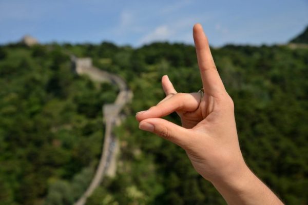 Wolfpack hand sign with the Great Wall of China in the background