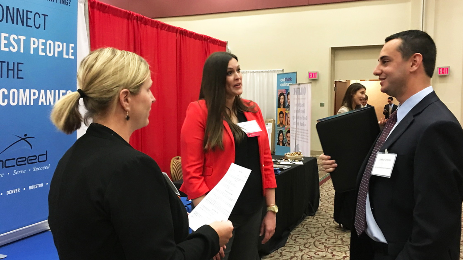 Professionally dressed people talk at a career event