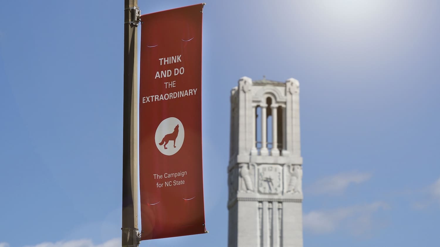 The NC State belltower with a Think and Do the extraordinary banner. Photo by Marc Hall