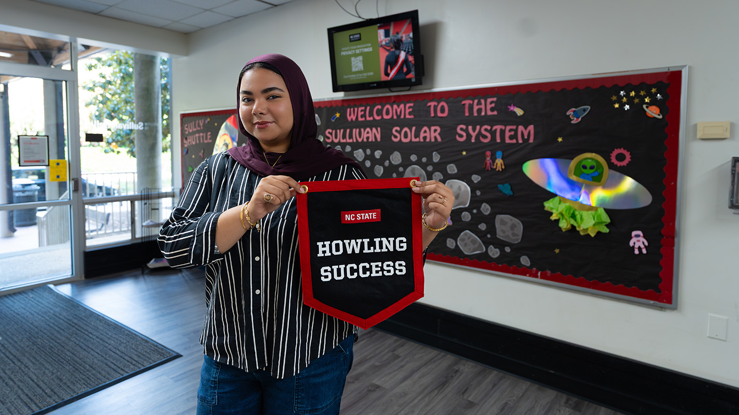 Malak Hassanein proudly displays her Howling Success banner in the lobby of Sullivan Residence Hall.