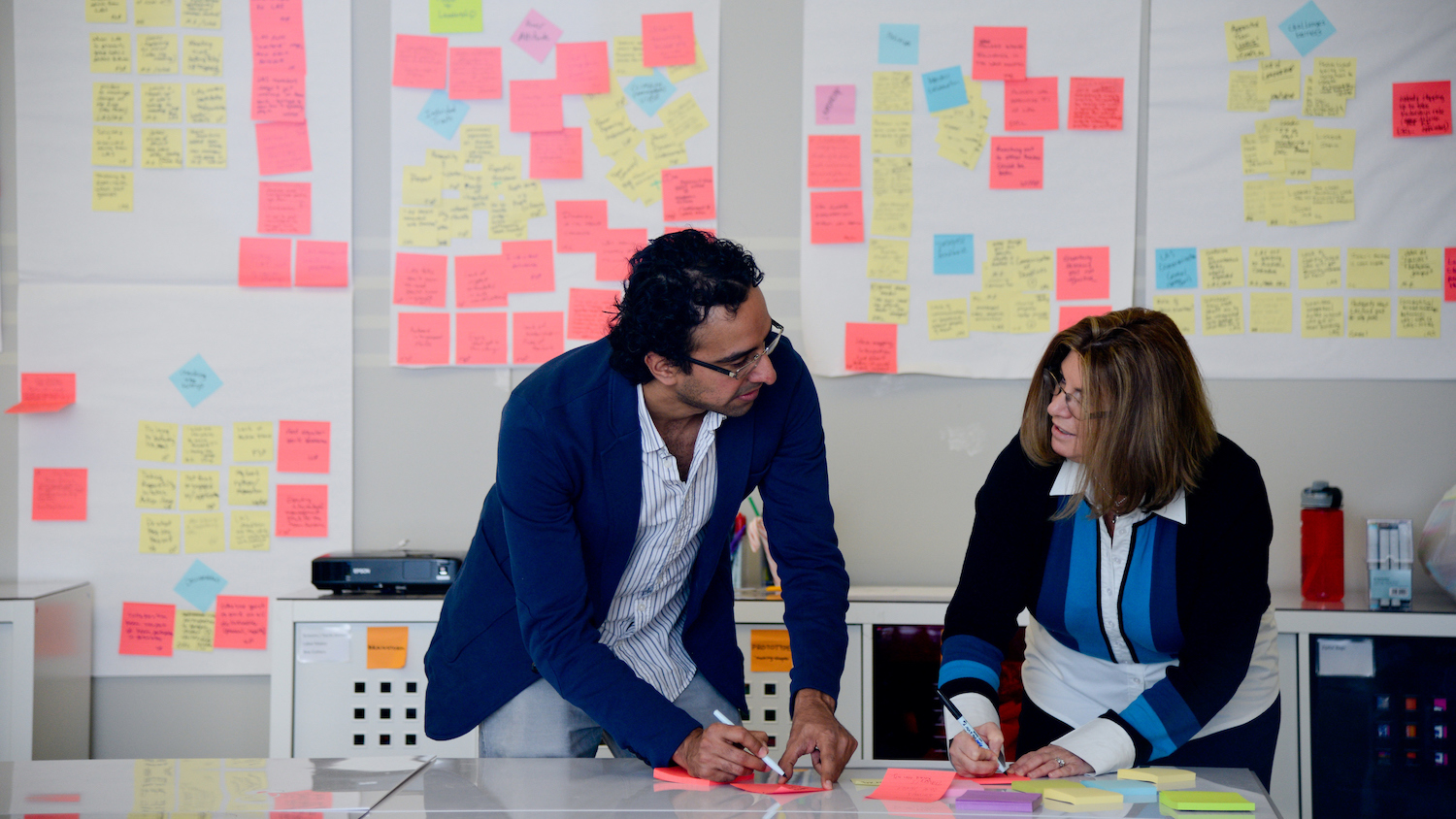 people working together in front of a kanban board